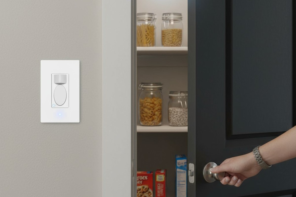 A mão de uma pessoa alcança uma maçaneta de despensa, e um interruptor de sensor de movimento na parede acaba de acender a luz brilhante dentro dela.