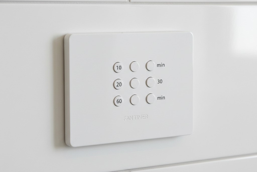 Interruptor temporizador para ventilador de exaustão Um interruptor branco montado na parede com botões verticais rotulados com incrementos de tempo como 10, 20, 30 e 60 minutos.
