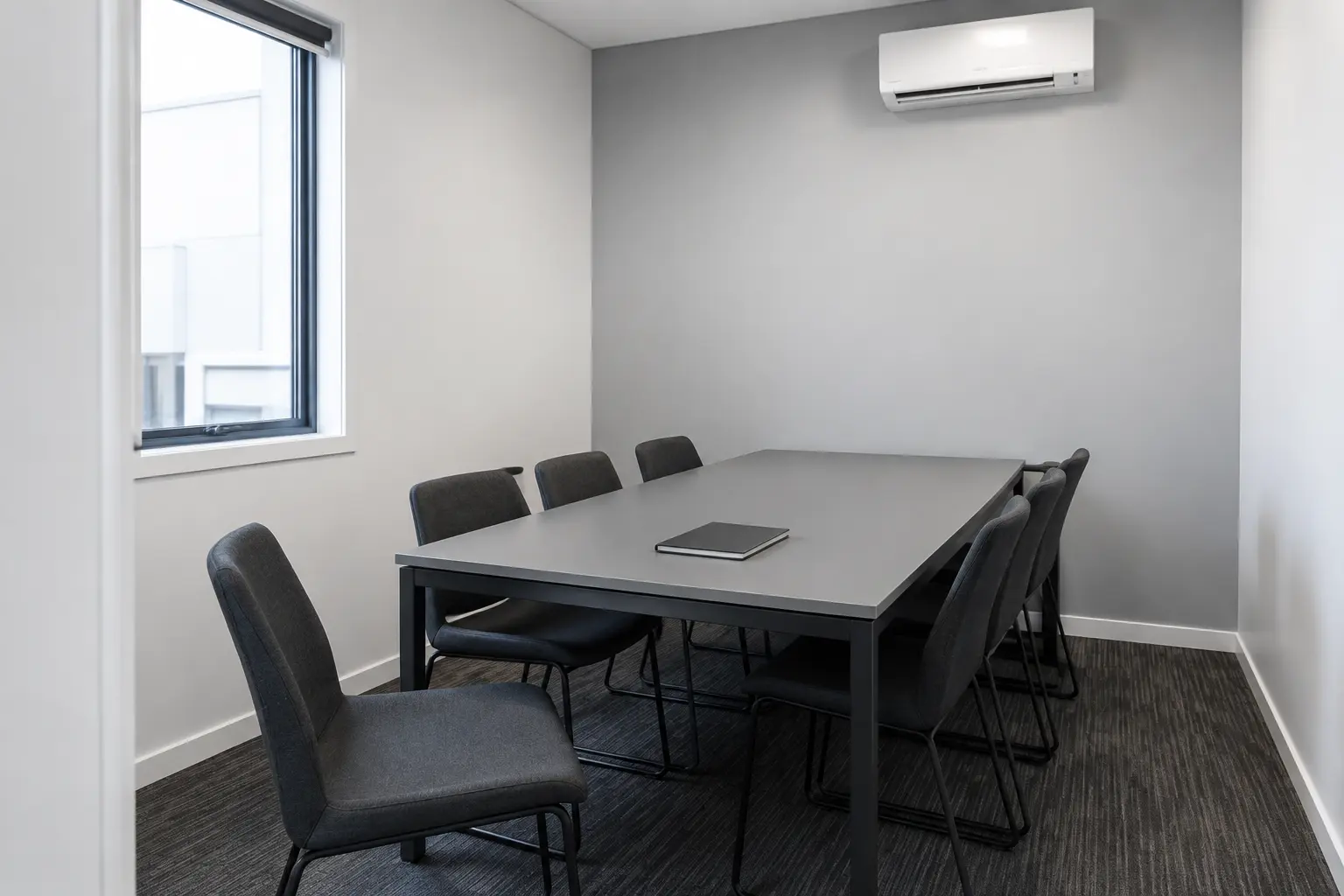 Empty meeting room with a pulled-back chair and wall-mounted air conditioner