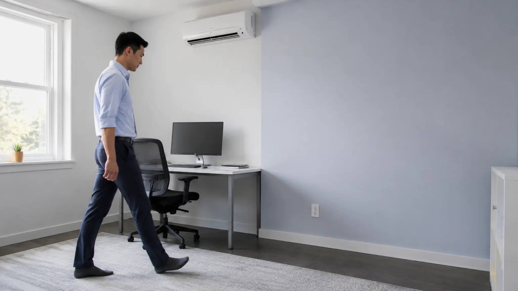 Person walking through an office beneath a wall-mounted air conditioner
